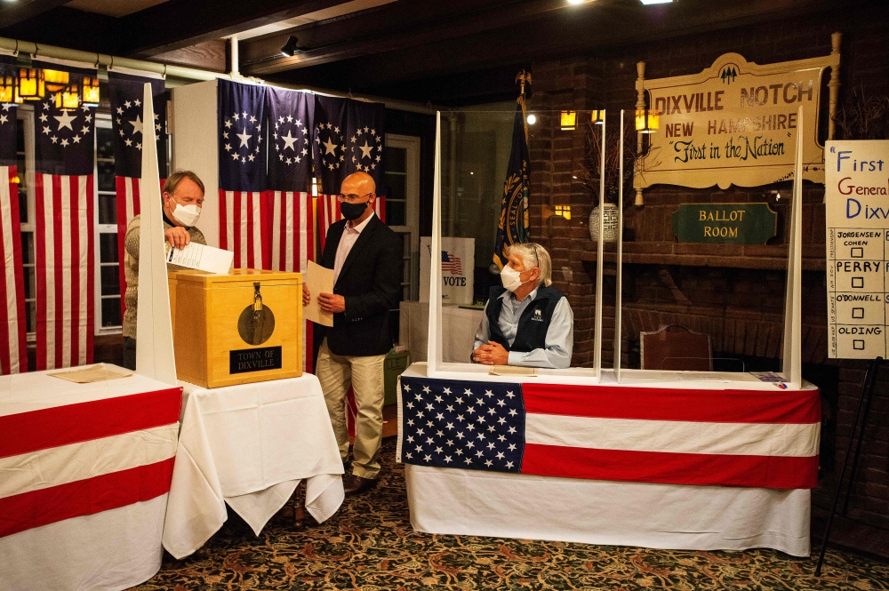 Tom Tillotson drops voters ballots into the ballot box at the Hale House at the historic Balsams Resort during midnight voting as part of the first ballots cast in the United States Presidential Election in Dixville Notch, New Hampshire on November 3, 202