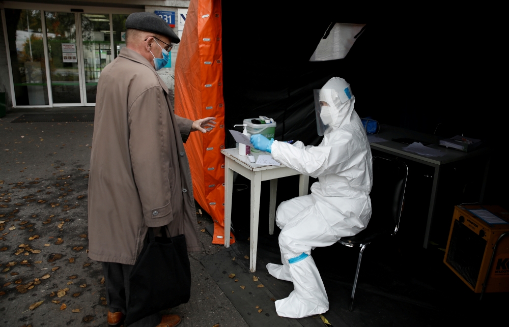 FILE PHOTO: A health worker in a protective suit gives a document to man, amid the coronavirus disease (COVID-19) outbreak, at a test center in front of a hospital in Warsaw, Poland October 27, 2020. REUTERS/Kacper Pempel/File Photo