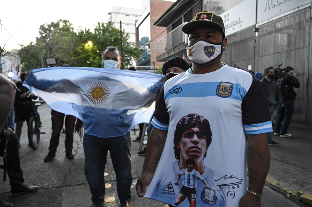 Supporters of Argentine former football star and coach of Gimnasia y Esgrima La Plata Diego Maradona gather outside the hospital where he will undergo brain surgery for a blood clot, in Olivos, Buenos Aires province, on November 3, 2020. / AFP / JUAN MABR