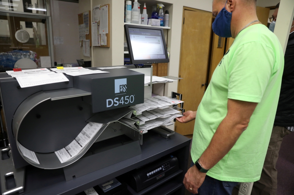 An election official processes absentee ballots at a central count facility on Election Day in Kenosha, Wisconsin, November 3, 2020. REUTERS/Daniel Acker