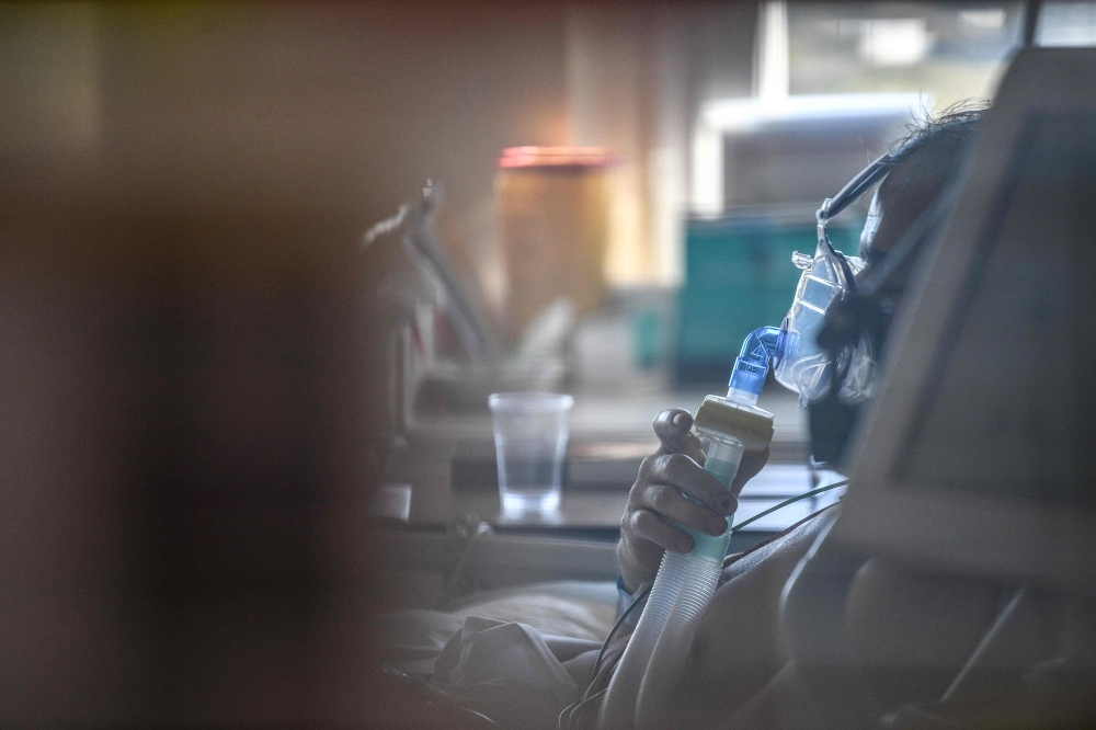  A patient infected with Covid-19 (novel coronavirus) sits in a bed in the intensive care unit at the Centre Hospitalier de l'Europe in Le Port-Marly, near Paris on November 4, 2020.   AFP / Anne-Christine POUJOULAT