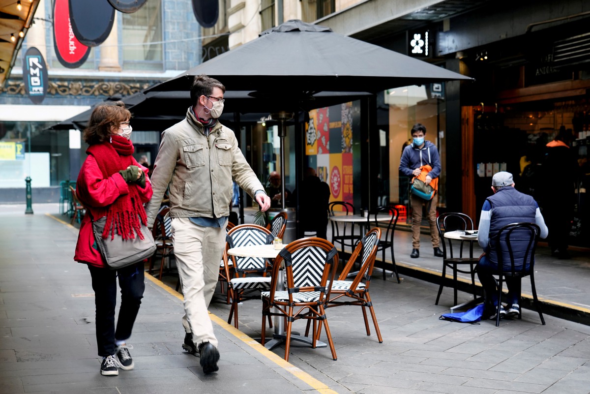 FILE PHOTO: People walk past a cafe after the coronavirus disease (COVID-19) restrictions were eased for the state of Victoria, in Melbourne, Australia, October 28, 2020. REUTERS/Sandra Sanders/File Photo
