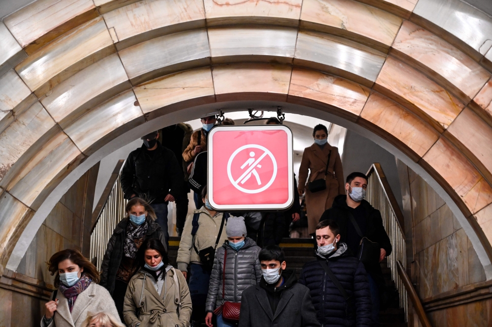 People wearing face masks to protect against the coronavirus disease walk down stairs at a metro station in Moscow on November 6, 2020. Russia confirmed new record of daily new Covid-19 cases (20,582) on November 6. / AFP / Kirill KUDRYAVTSEV
