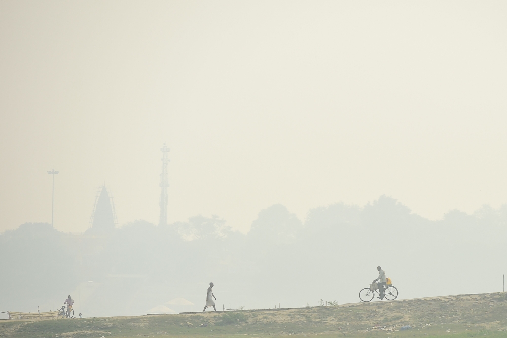 Commuters are seen amid heavy smog conditions and fog, in Allahabad on November 6, 2020. / AFP / SANJAY KANOJIA