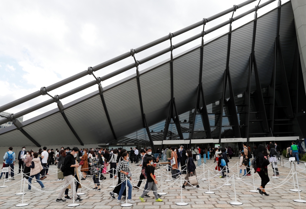 Spectators wearing protective masks amid the coronavirus disease (COVID-19) outbreak enter the venue of Friendship and Solidarity Competition, the first international event at a Tokyo Olympic venue since the Games were postponed in March due to the COVID-