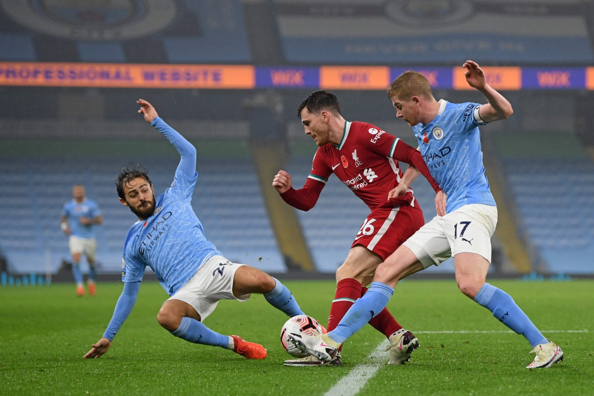 Liverpool's Scottish defender Andrew Robertson (C) gets tackled by Manchester City's Belgian midfielder Kevin De Bruyne (R) and Manchester City's Portuguese midfielder Bernardo Silva (L) during the English Premier League football match between Manchester 