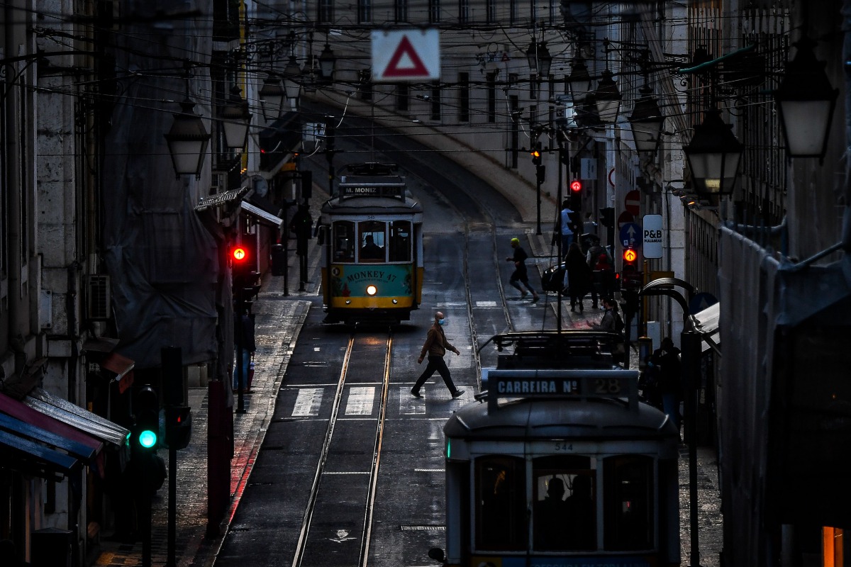 A man wearing a face mask crosses a street in downtown Lisbon on November 7, 2020. / AFP / PATRICIA DE MELO MOREIRA
