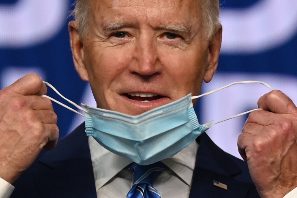 In this file photo former Democratic Presidential candidate Joe Biden removes his facemask as he arrives to speak at the Chase Center in Wilmington, Delaware, on November 4, 2020. / AFP / JIM WATSON