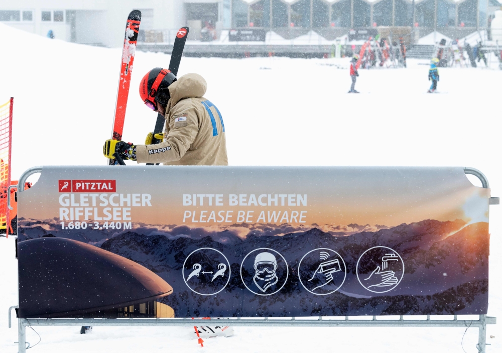 A skier prepares his skis next to the covid-19 safety instruction sign at Pitztal glacier, Austria on October 29, 2020. After some of its economically crucial ski resorts became bywords for coronavirus clusters in the first wave of the pandemic, Austria w