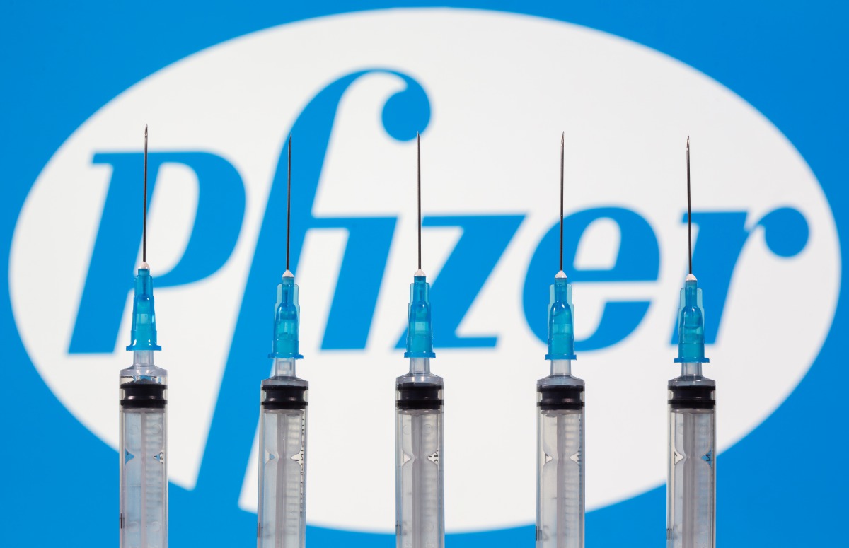 Syringes are seen in front of a displayed pfizer logo in this illustration taken, November 10, 2020. REUTERS/Dado Ruvic/Illustration
