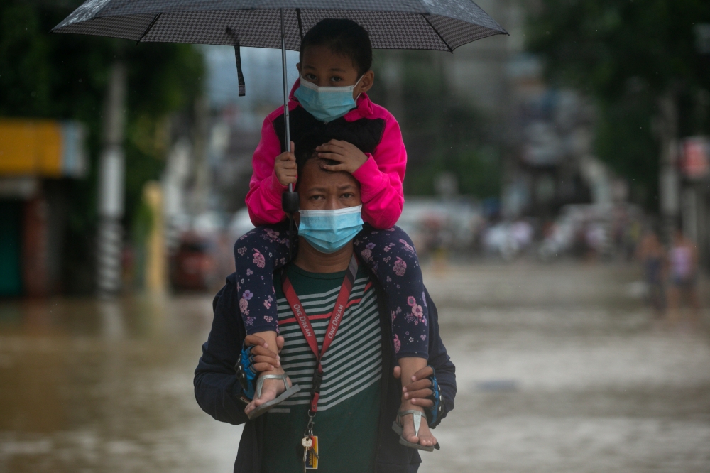 A man carries a child on his shoulders as he wades through a flooded road following Typhoon Vamco, in Marikina, Metro Manila, Philippines, November 12, 2020. REUTERS/Eloisa Lopez