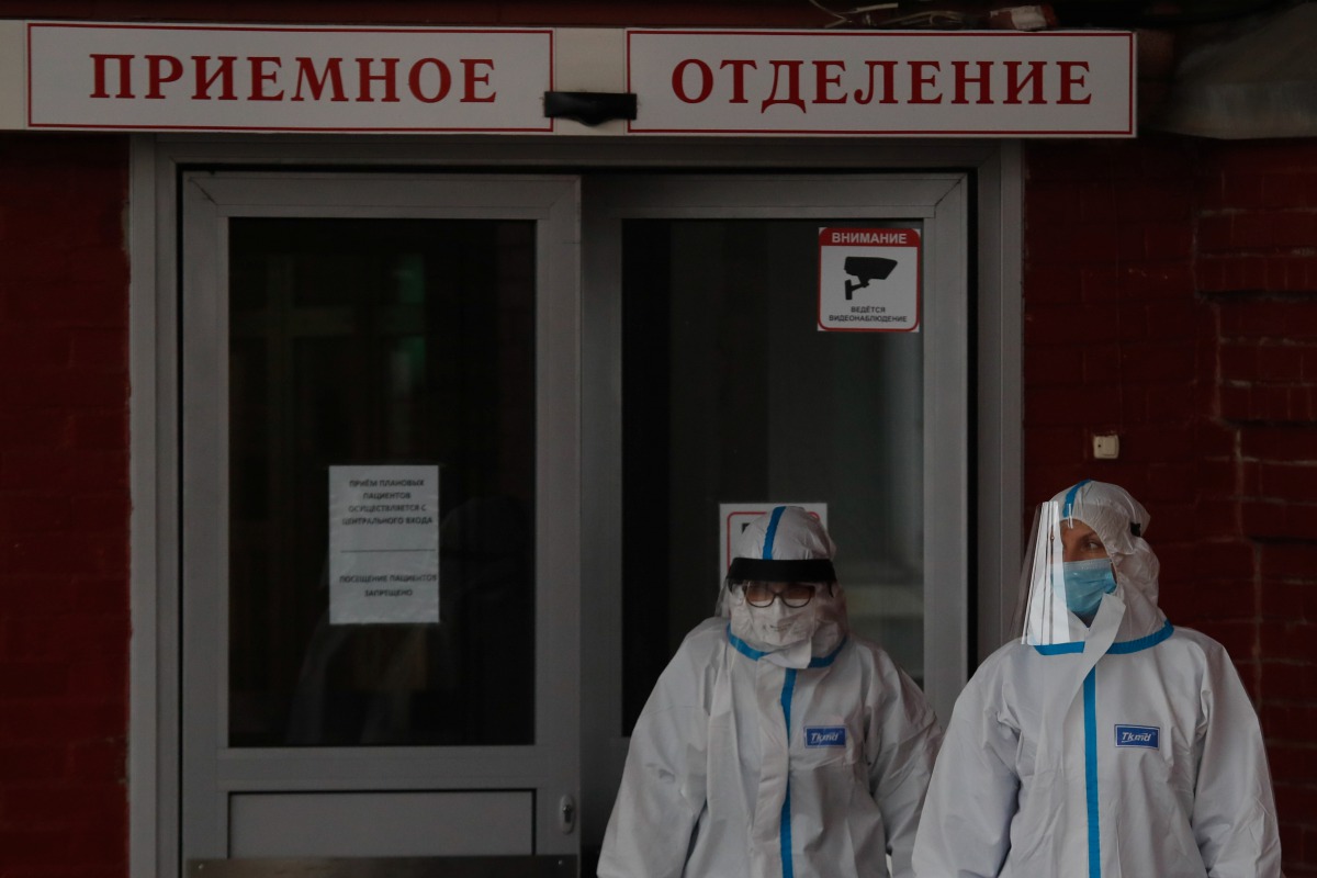 Medical specialists wearing protective gear walk outside a hospital, amid the outbreak of the coronavirus disease (COVID-19) in Saint Petersburg, Russia November 11, 2020. The sign reads: 