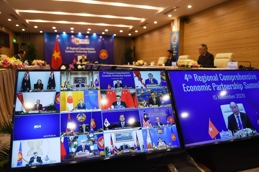 Vietnam's Prime Minister Nguyen Xuan Phuc is pictured on the screen (R) as he addresses his counterparts during the 4th Regional Comprehensive Economic Partnership (RCEP) Summit at the Association of Southeast Asian Nations (ASEAN) summit being held onlin