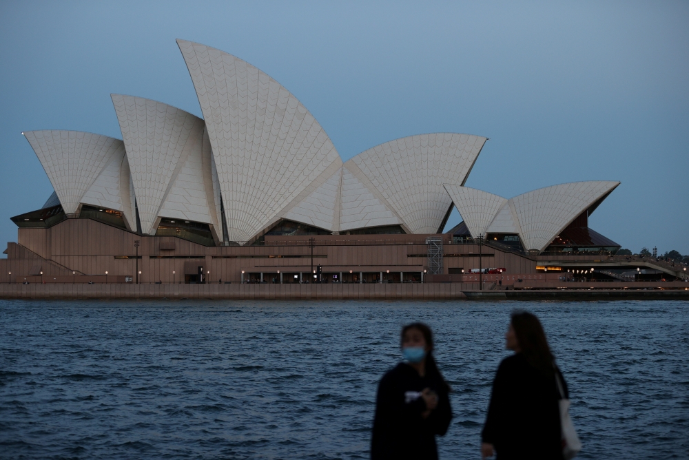 People stand on the harbour waterfront near the Sydney Opera House in Sydney, Australia, November 11, 2020. REUTERS/Loren Elliott/File Photo