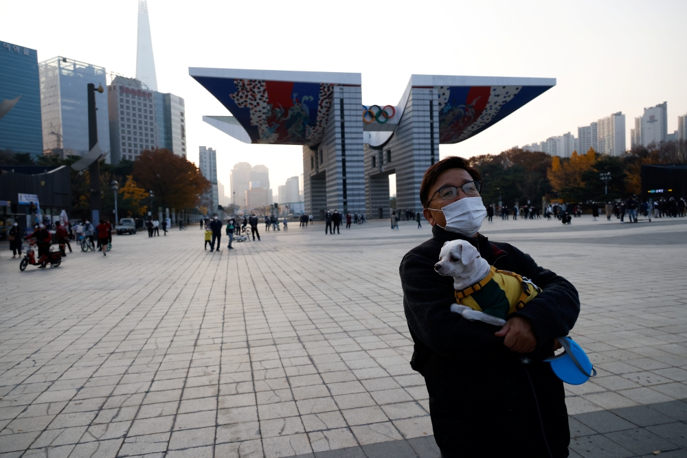 A man holding a pet dog takes a walk amid the coronavirus disease (COVID-19) pandemic at a park in Seoul, South Korea, November 13, 2020. REUTERS/Kim Hong-Ji