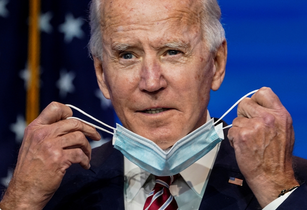 U.S. President-elect Joe Biden removes his face mask to speak about the U.S. economy after attending a briefing in Wilmington, Delaware, U.S., November 16, 2020. REUTERS/Kevin Lamarque 