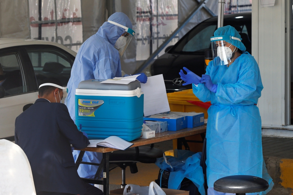 Healthcare workers prepare to take nose samples to check for the coronavirus disease (COVID-19) at a drive-thru testing station in Amman, Jordan, November 17, 2020. REUTERS/Muhammad Hamed