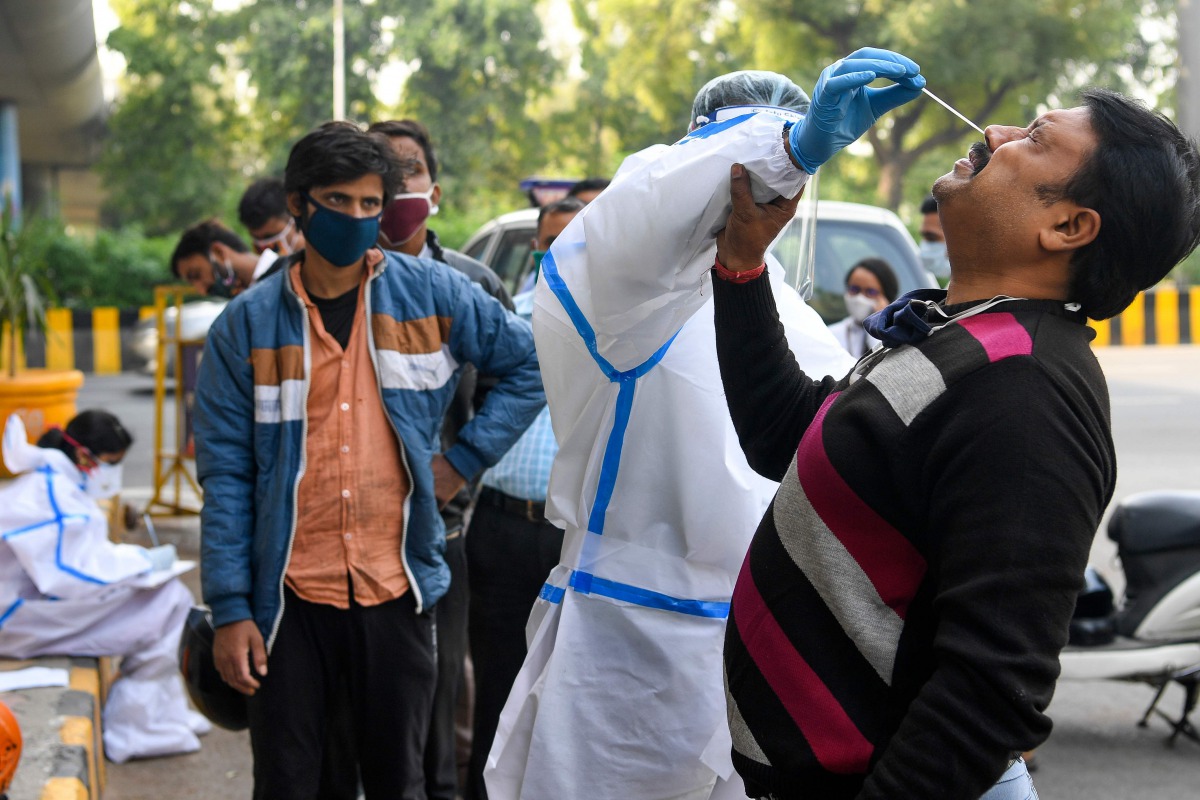A medical worker wearing protective gear collects a nasal swab sample from a man for a Rapid Antigen Test (RAT) for the Covid-19 coronavirus as Noida authorities started conducting random coronavirus testing on commuters arriving from Delhi at Delhi-Uttar