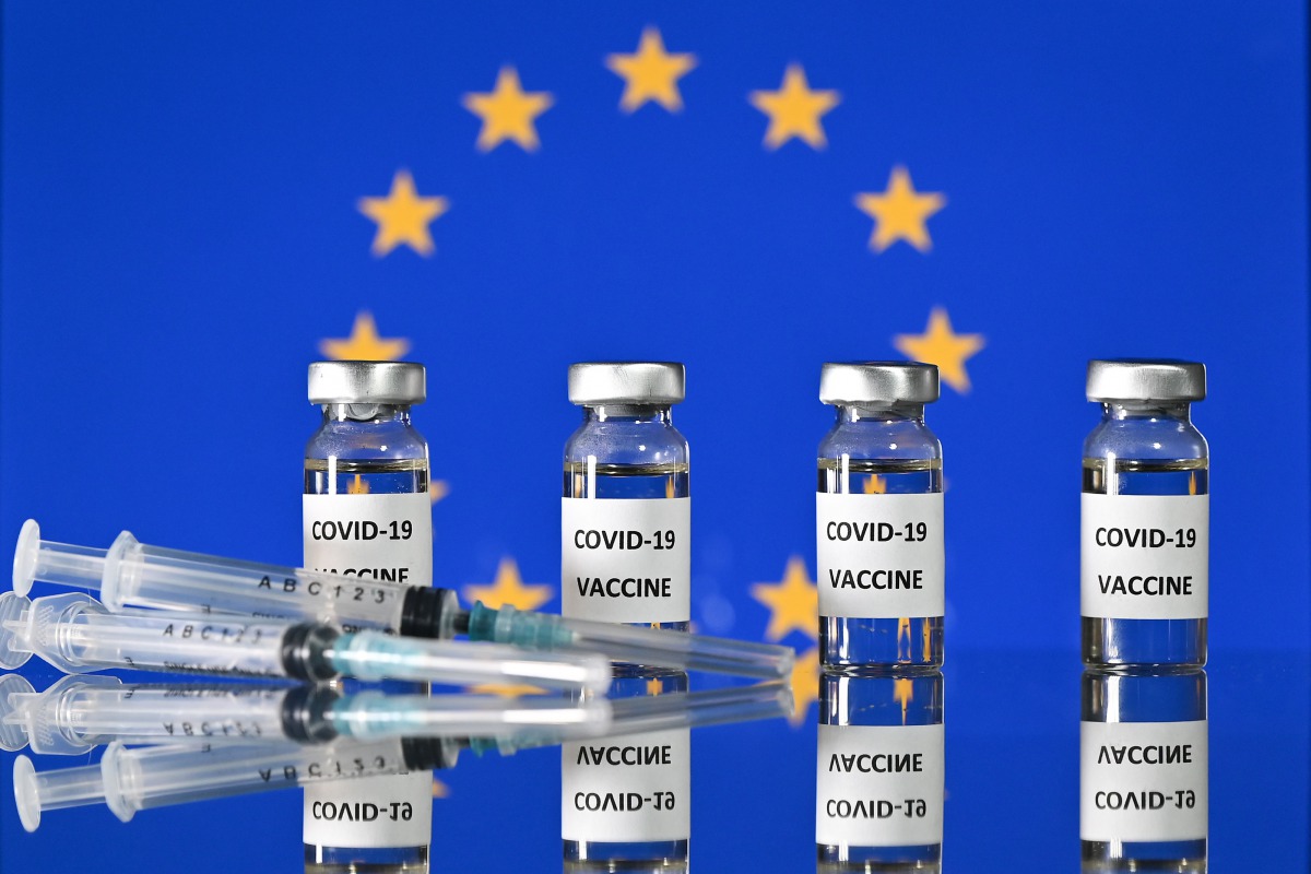An illustration picture shows vials with Covid-19 Vaccine stickers attached, and syringes, with a flag of the European Union, on November 17, 2020. / AFP / JUSTIN TALLIS
