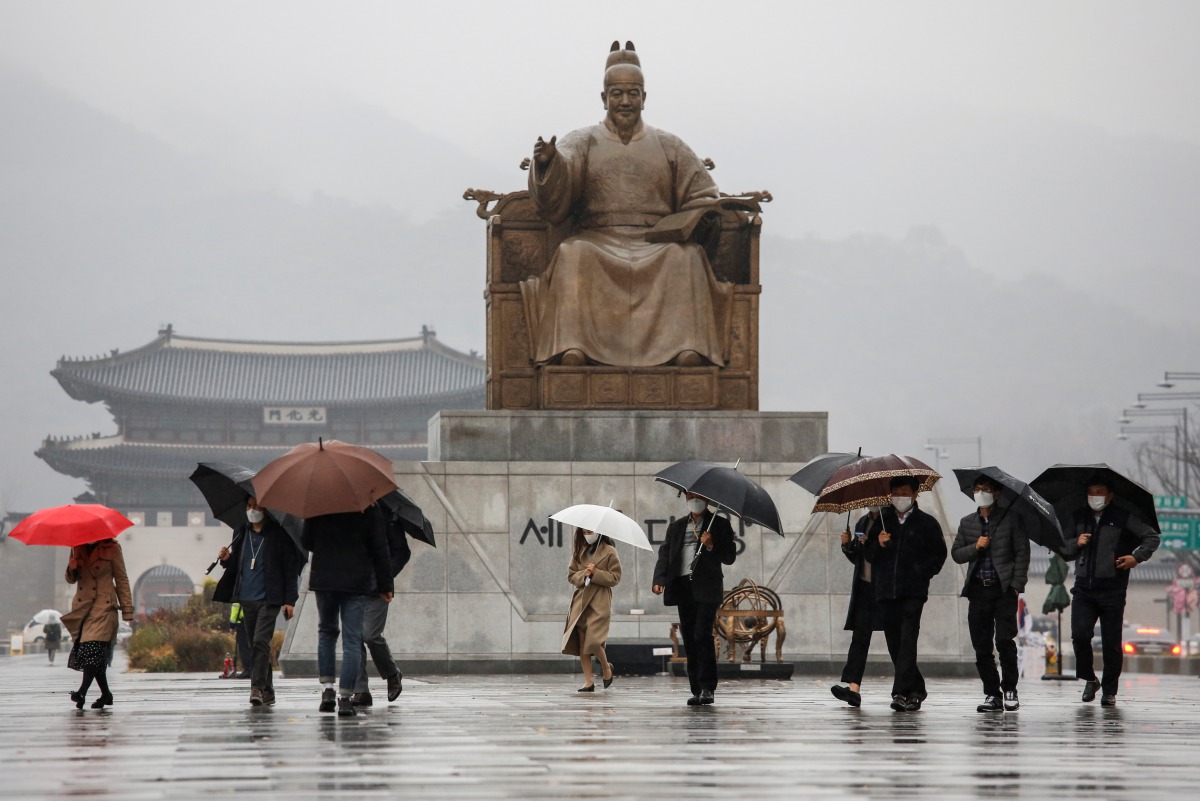 Pedestrians wearing masks walk with umbrellas as it rains amid the coronavirus disease (COVID-19) pandemic in central Seoul, South Korea, November 19, 2020. REUTERS/Heo Ran
