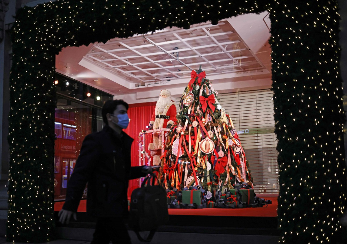 A pedestrian wearing a face mask or covering due to the COVID-19 pandemic, walk past Christmas-themed window display at Selfridges department store in central London on November 17, 2020. Britain has been the worst-hit nation in Europe recording more than