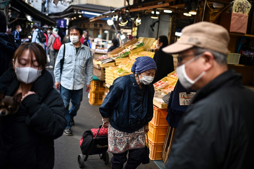 An elderly woman walks though an alley at a market in Tokyo's Tsukiji area on November 21, 2020. / AFP / Charly TRIBALLEAU