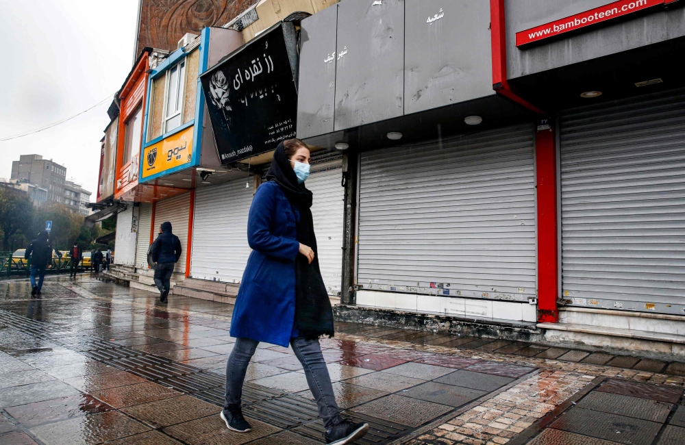 Pedestrians, mask-clad due to the Covid-19 coronavirus pandemic, walk past closed shops along a street in Iran's capital Tehran on November 21, 2020, as the Iranian government announced new pandemic-countering measures. AFP / STR