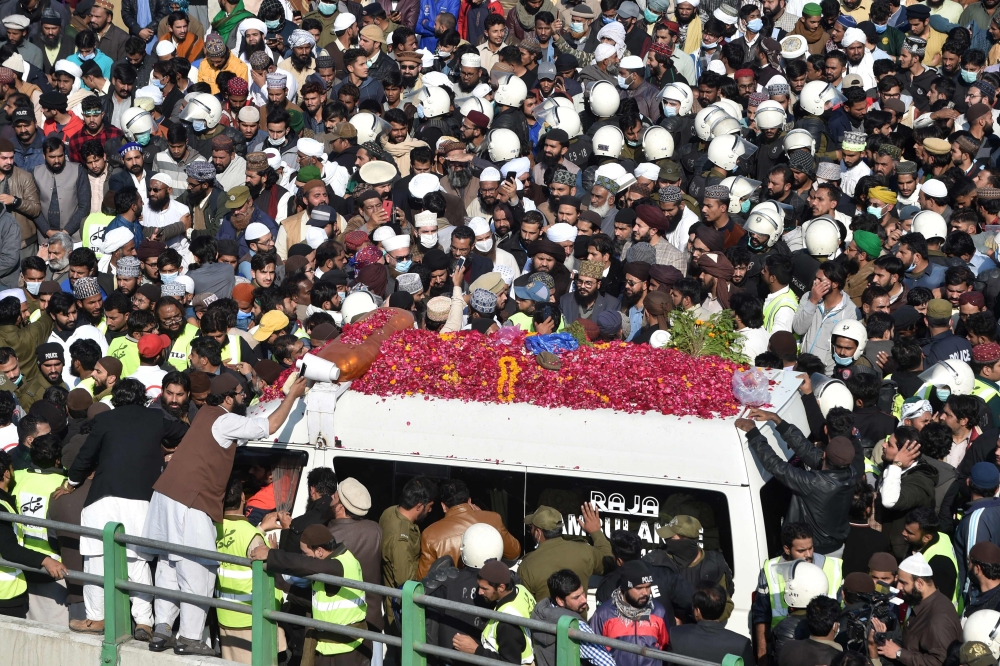 Activists and supporters of Tehreek-e-Labbaik Pakistan (TLP) gather around an ambulance carrying the coffin of Khadim Hussain Rizvi, founder of TLP, during his funeral ceremony in Lahore on November 21, 2020.  AFP / Arif ALI