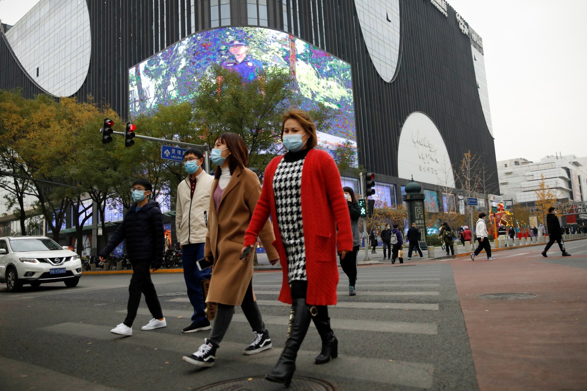 People wearing face masks walk near a shopping complex amid the coronavirus disease (COVID-19) outbreak in Beijing, China November 16, 2020. REUTERS/Tingshu Wang
