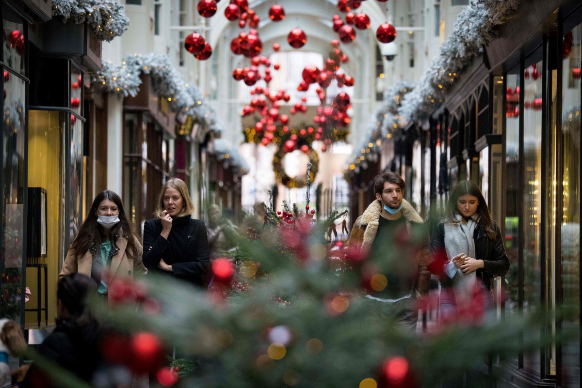 Pedestrians wearing face masks due to the COVID-19 pandemic, walk past Christmas-themed window displays inside Burlington Arcade in central London, on November 23, 2020. Prime Minister Boris Johnson's latest plan is to roll out mass testing to the hardest