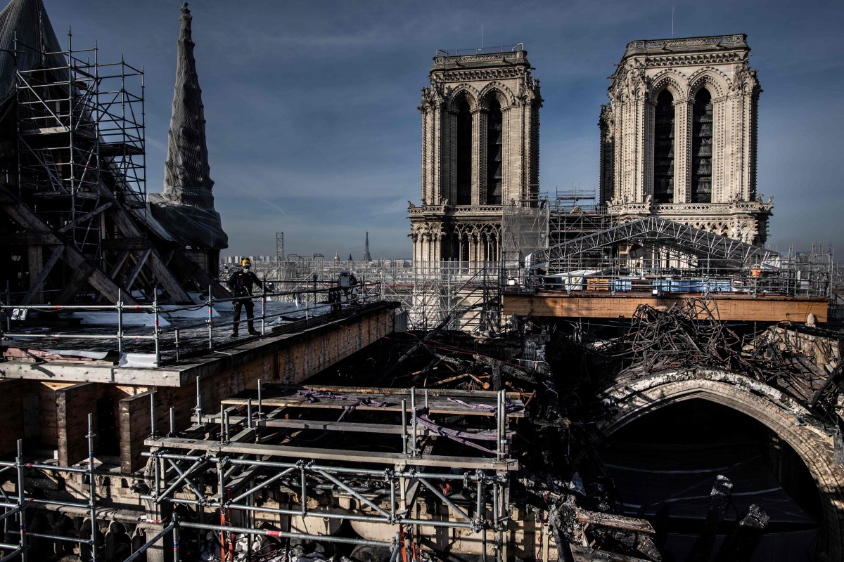 Workers work to remove the burnt scaffolding which hampered the safety of Notre-Dame from the roof of the cathedral damaged by the April 15, 2019 fire on November 24, 2020 in Paris. AFP / Martin BUREAU
