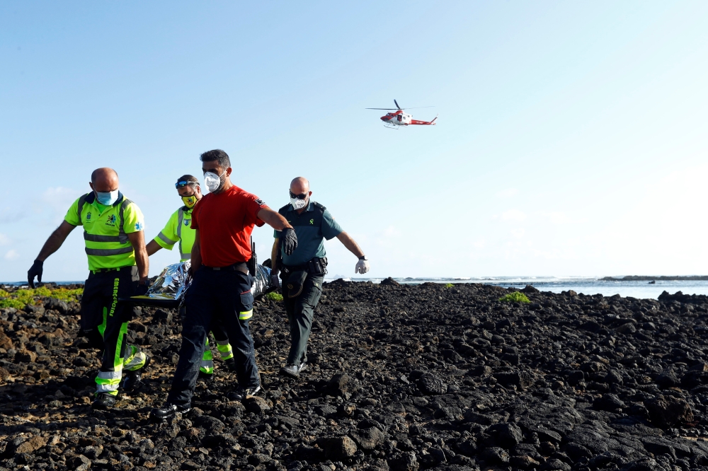 Rescue workers carry the body of a dead person after a boat with 35 migrants from the Maghreb region capsized in the beach of Orzola, in the Canary Island of Lanzarote. Reuters/Borja Suarez