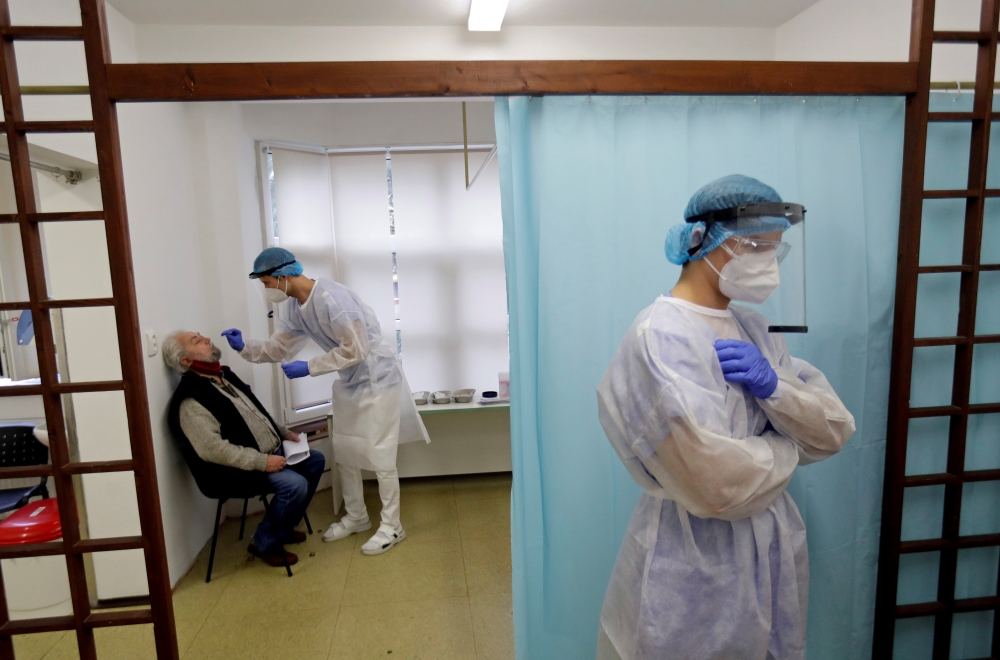 David Antos, 23, a medical student, wearing protective equipment collects a swab sample from a person at a coronavirus disease (COVID-19) testing center in Prague, Czech Republic, October 30, 2020. REUTERS/David W Cerny/File Photo