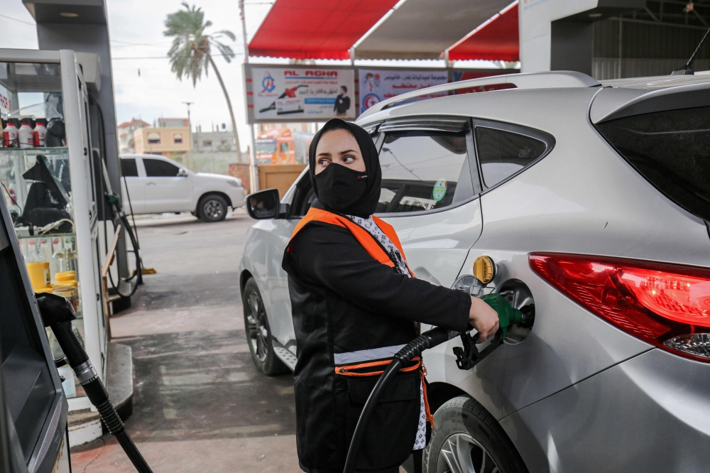 Salma al-Najjar, a 16-year-old Palestinian who works at a petrol station to help her family with income, refuels a car in Khan Yunis in southern Gaza Strip, 24 November 2020. / AFP / SAID KHATIB