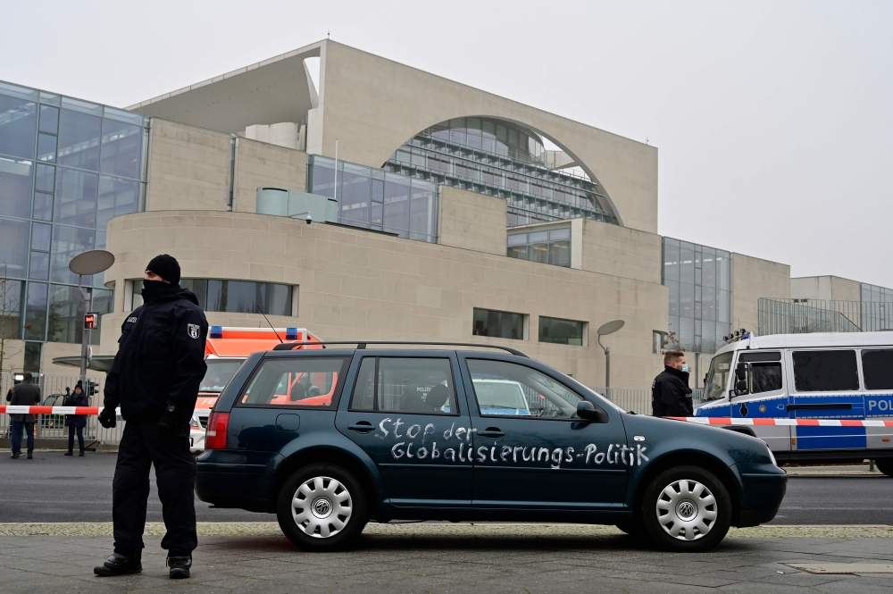 Policemen guard a car with the lettering 'Stop globalisation politics' painted on its doors after it drove into the gate of the German Chancellery and was removed by police, in central Berlin on November 25, 2020. German police said on November 25 they ha