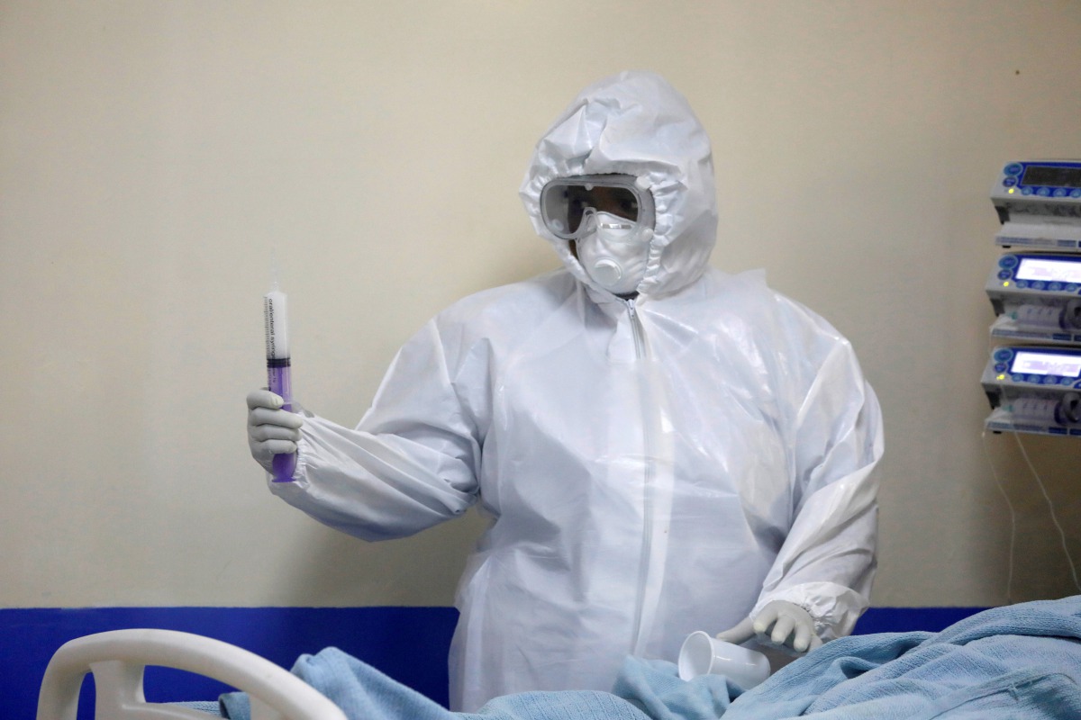 FILE PHOTO: A member of the medical staff dressed in a protective suit holds a syringe as he treats a coronavirus disease patient inside the COVID-19 ICU of Machakos Level 5 Hospital, in Machakos, Kenya October 28, 2020. Picture taken October 28, 2020. RE
