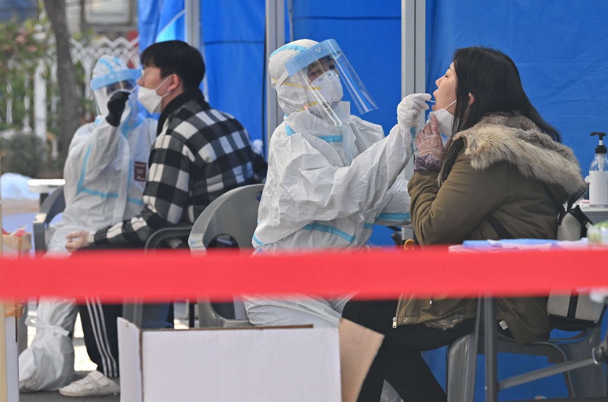 Medical staff members wearing protective gear take samples for the Covid-19 test from visitors at a testing station in SEOUL on November 27, 2020. / AFP / Jung Yeon-je
