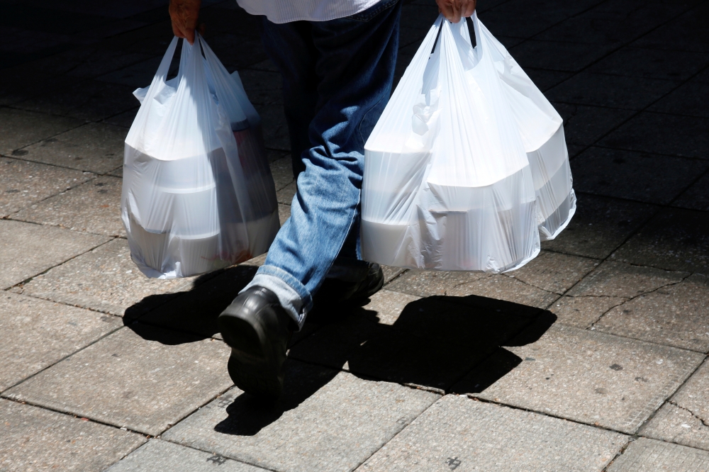 A man carries plastic bags containing take-away food after the government banned dine-in services, following the coronavirus disease (COVID-19) outbreak in Hong Kong, China July 29, 2020. REUTERS/Tyrone Siu/File Photo