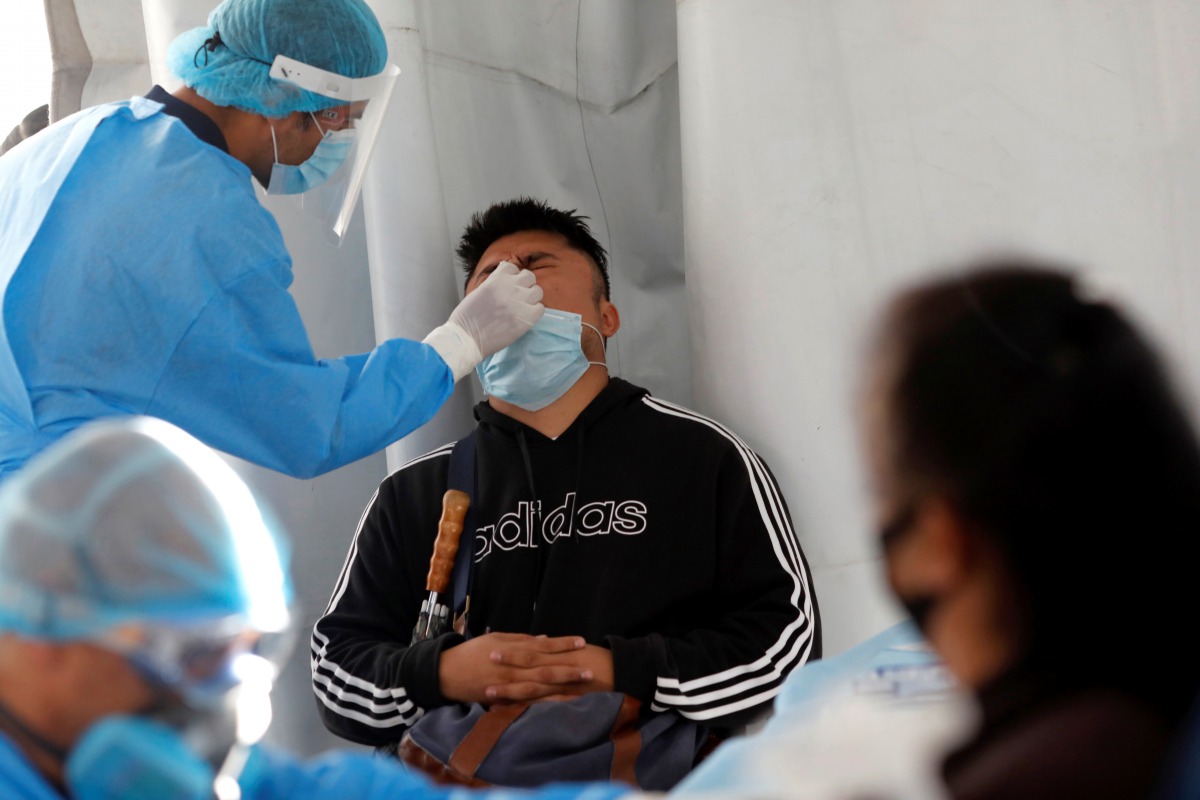 A healthcare worker wearing personal protective equipment (PPE) takes a swab sample from a man for coronavirus disease (COVID-19) rapid antigen testing outside the Azteca stadium in Mexico City, Mexico, November 25, 2020. REUTERS/Henry Romero
