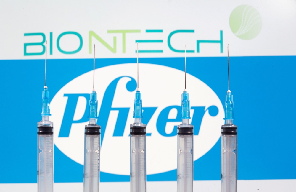 Syringes are seen in front of displayed Biontech and Pfizer logos in this illustration taken November 10, 2020. REUTERS/Dado Ruvic/File Photo