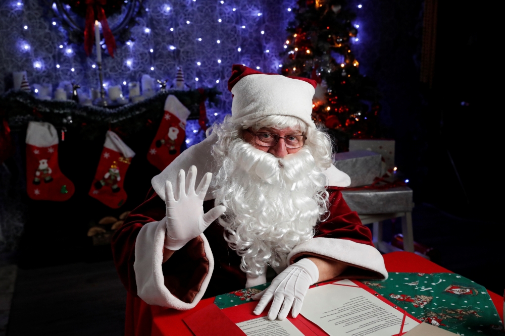 Janos Nemes, dressed as Santa Claus, waves as he interacts with children by video in a photo studio, amid the coronavirus disease (COVID-19) outbreak, in Budapest, Hungary, December 1, 2020. Picture taken December 1, 2020. REUTERS/Bernadett Szabo