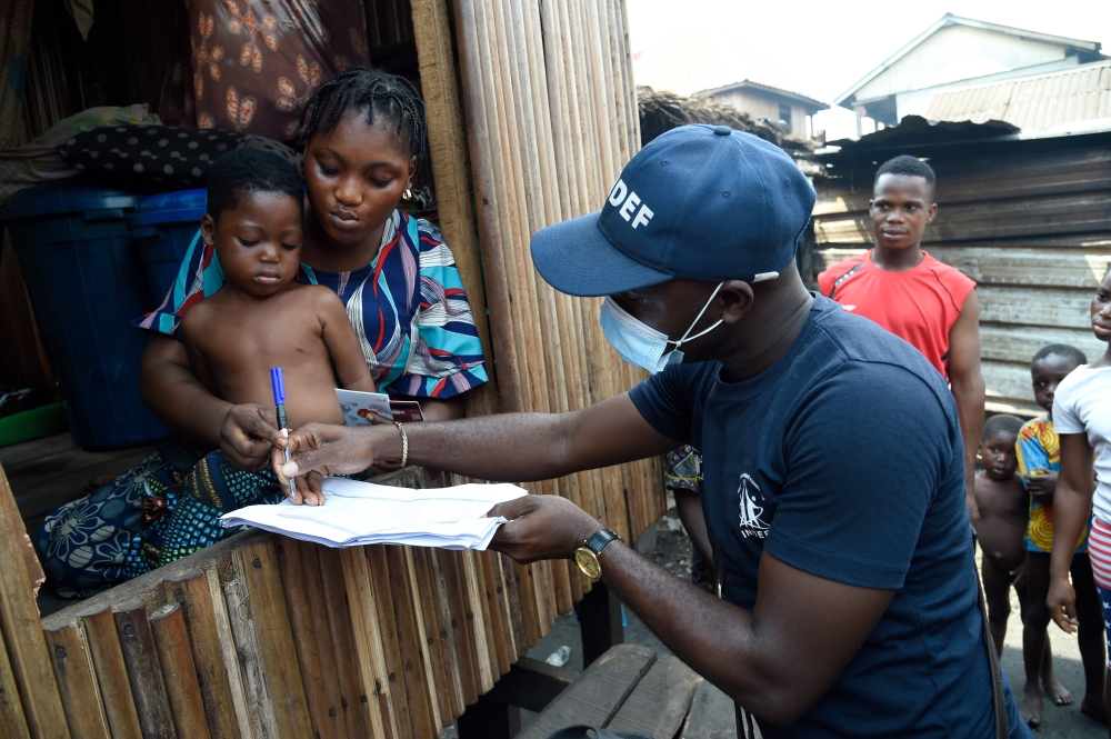 Bidemi Aye receives a pre-paid debt card for cash and food provided by World Food Programme (WFP) in a makeshift home in the Makoko riverine slum settlement in Lagos on November 27, 2020.  AFP / PIUS UTOMI EKPEI
