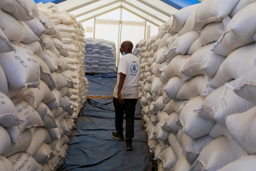 World Food Programme employee walks between sacks of food at the Um Rakuba refugee camp which houses Ethiopian refugees fleeing the fighting in the Tigray region, on the Sudan-Ethiopia border in Sudan, November 29, 2020. REUTERS/Baz Ratner