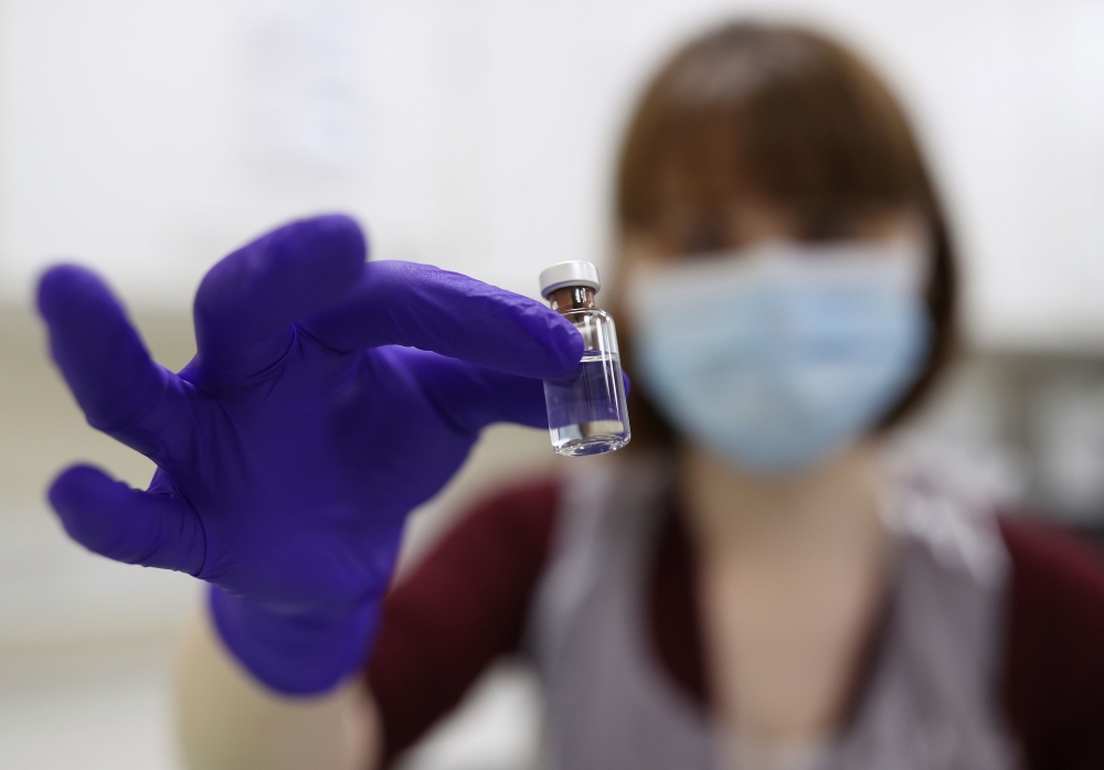 An NHS pharmacy technician holds a vial as she simulates the preparation of the Pfizer-BioNTech coronavirus vaccine, during a staff training session ahead of the vaccine's rollout next week, at the Royal Free Hospital in London on December 4, 2020. / AFP 