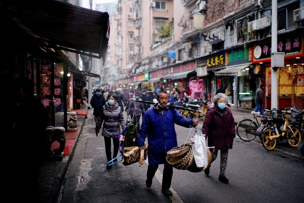People wearing protective masks walk at a street market almost a year after the start of the coronavirus disease (COVID-19) outbreak, in Wuhan, Hubei province, China December 7, 2020. Picture taken December 7, 2020. REUTERS/Aly Song