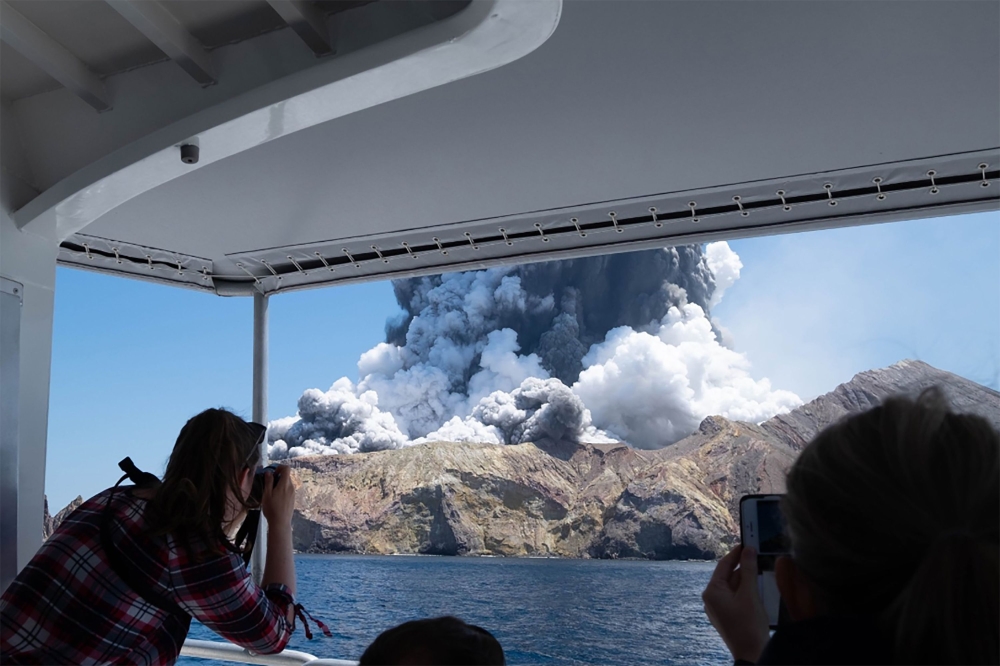 This handout file photograph released courtesy of Michael Schade and taken on December 9, 2019 shows the volcano on New Zealand's White Island spewing steam and ash moments after it erupted. AFP Photo/ Courtesy of Michael Schade 