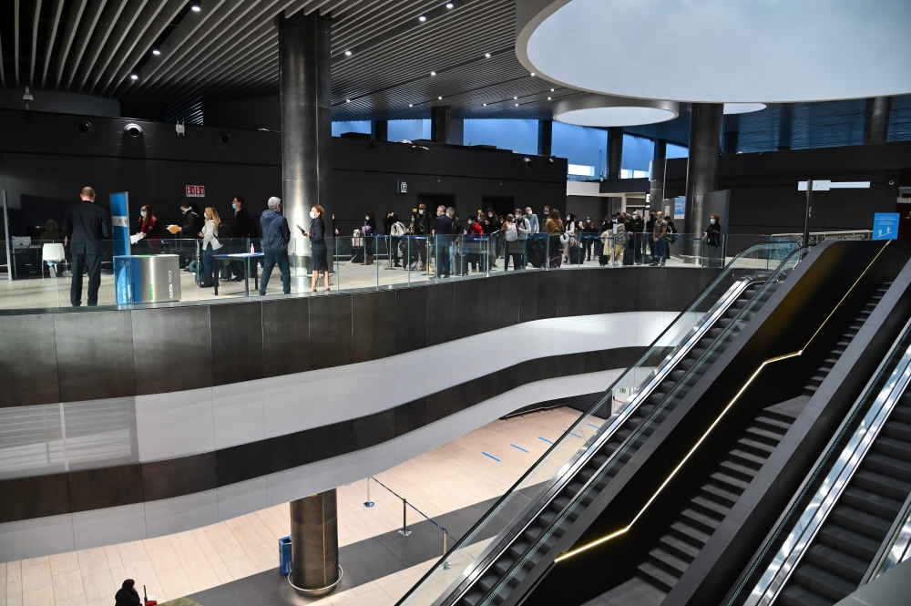 Passengers who just landed from New York on an Alitalia flight wait in line as they prepare to undergo a rapid antigen swab test for COVID-19 on December 9, 2020 at a testing station set up at Rome's Fiumicino airport, as part of Italy's first coronavirus