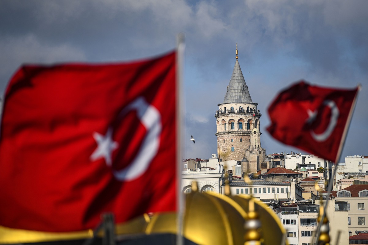 In this photo taken on December 6, 2020 the Galata tower is pictured next to Turkish national flags in Istanbul during a week-end curfew aimed at curbing the spread of the Covid-19 pandemic caused by the novel coronavirus. AFP / Ozan KOSE
