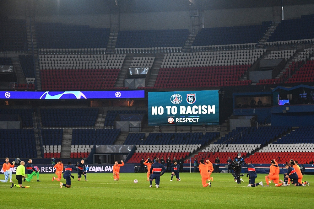 Football players and referees kneel on the pitch against racism before the UEFA Champions League group H football match between Paris Saint-Germain (PSG) and Istanbul Basaksehir FK at the Parc des Princes stadium in Paris, on December 9, 2020. / AFP / FRA