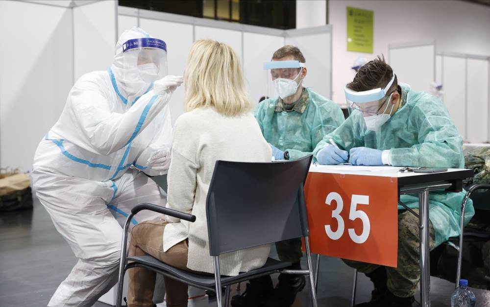 Medical personnel swabs the throat of a patient as he administers a COVID-19 test on December 12, 2020, at the exhibition hall in Graz. Mass detection tests will be held in Styria on December 12 and 13, 2020.  AFP /  ERWIN SCHERIAU